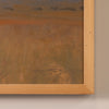 Close-up of a framed painting showing textured earthy brown and orange brushstrokes, with a light natural wood frame against a neutral wall.