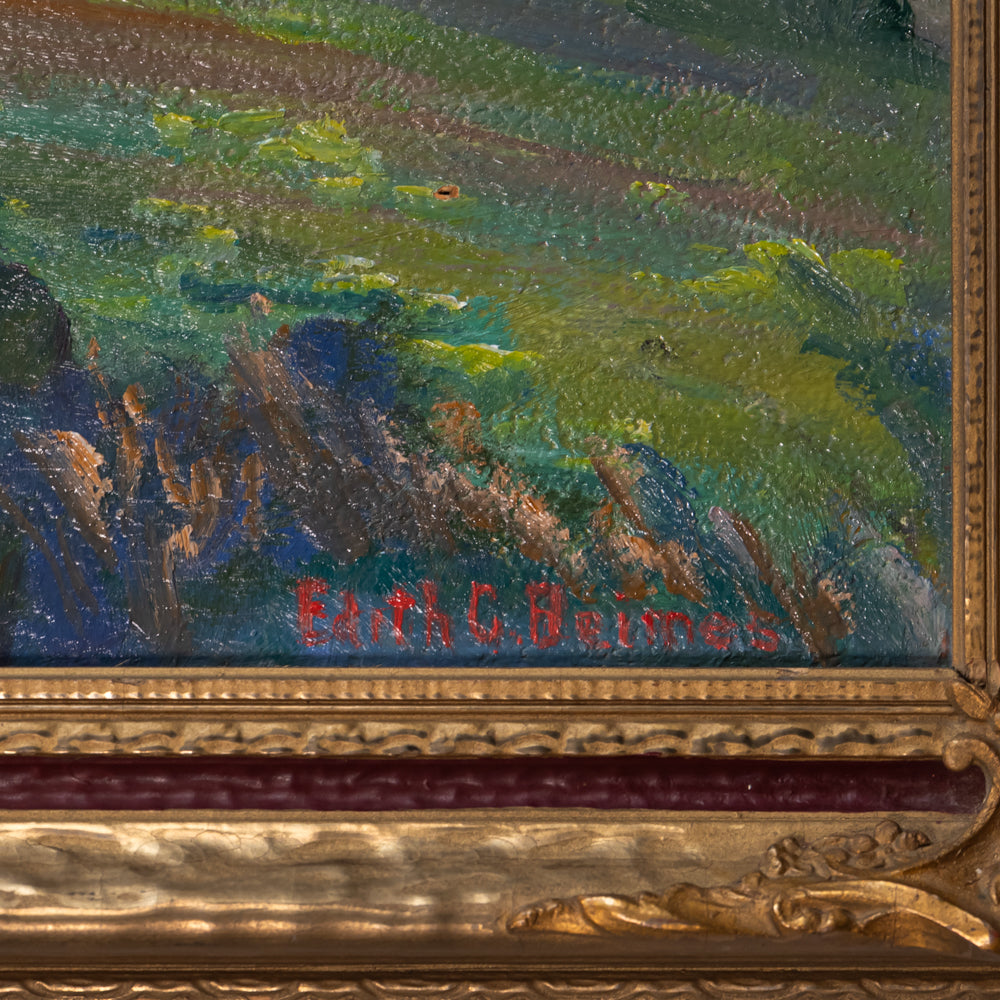 Close-up of an oil painting showing a landscape with green and blue brushstrokes, part of an ornate gold frame, and red painted signature text near the bottom.