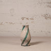 Ceramic vase with green stripes on a textured surface and wall background