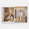 Open book showing two interior design images: a living room with a person lounging on a sofa and a colorful door.