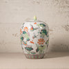 Decorative ceramic jar with floral and butterfly design on a textured surface.