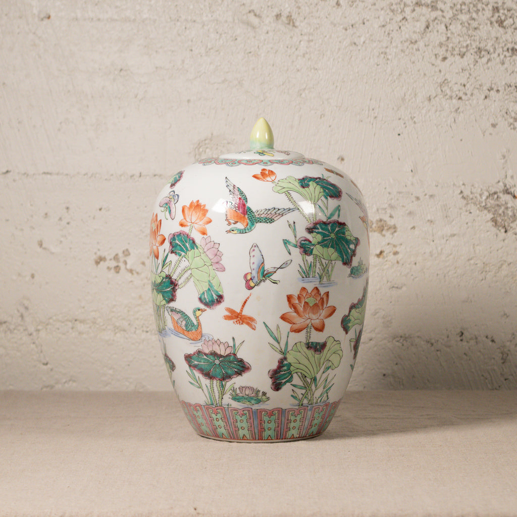 Decorative ceramic jar with floral and butterfly design on a textured surface.