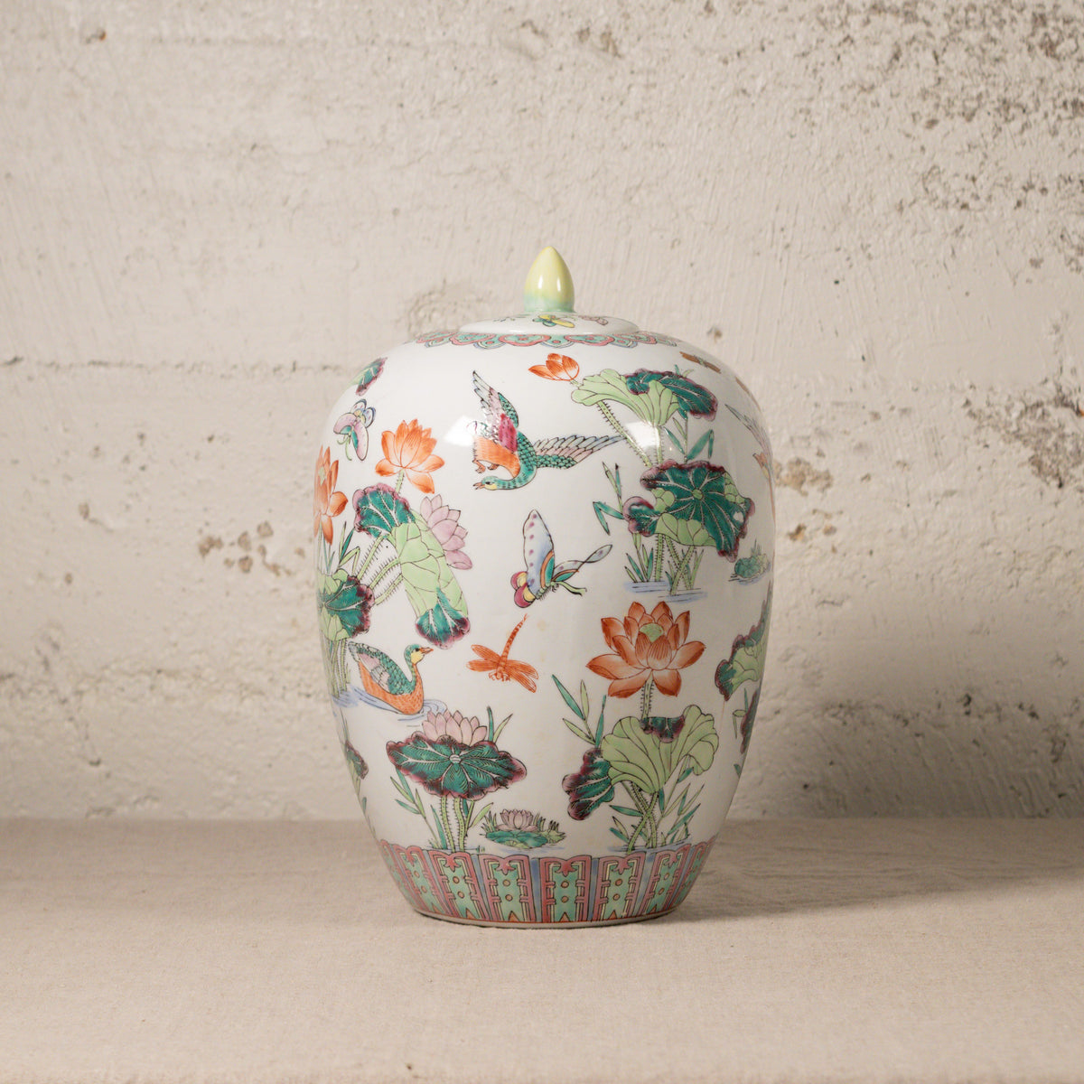 Decorative ceramic jar with floral and butterfly design on a textured surface.