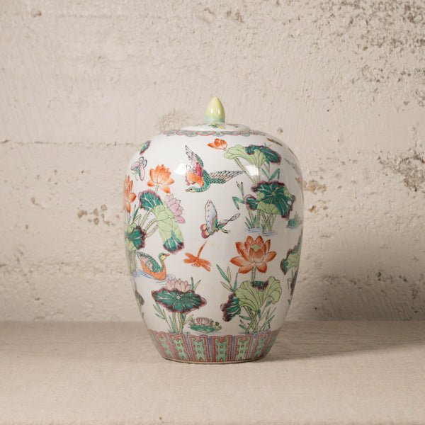 Decorative ceramic jar with floral and butterfly design on a textured surface.