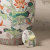 Decorative ceramic jar with floral design and matching lid on a neutral background