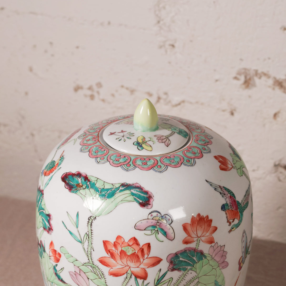 Decorative ceramic jar with floral and bird patterns on a textured beige background