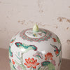 Decorative ceramic jar with floral and bird patterns on a textured beige background