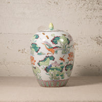 Decorative ceramic jar with colorful floral and bird design on a textured surface.