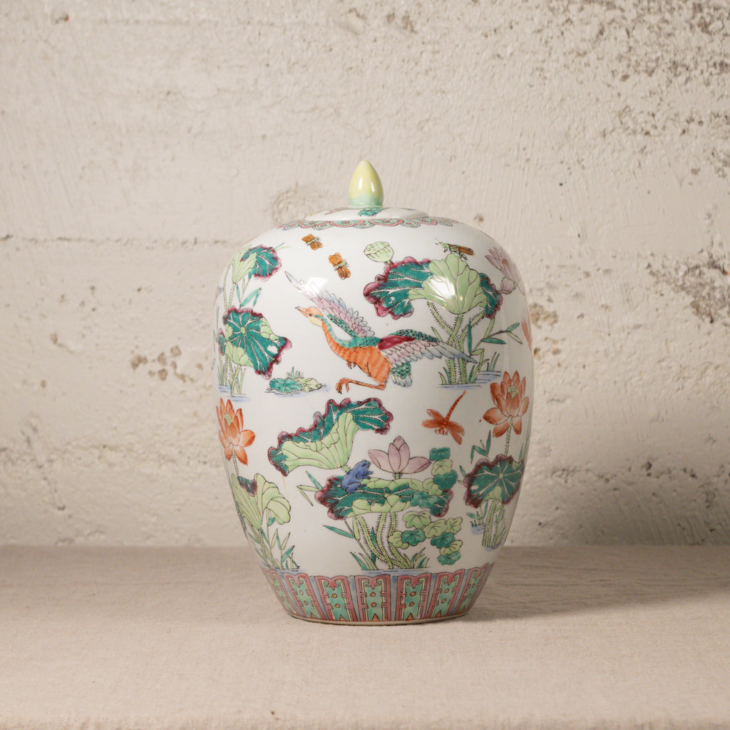 Decorative ceramic jar with colorful floral and bird design on a textured surface.
