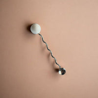 Wall-mounted lamp with a curved arm and spherical ends on a beige background