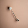 Wall-mounted lamp with a curved arm and spherical ends on a beige background