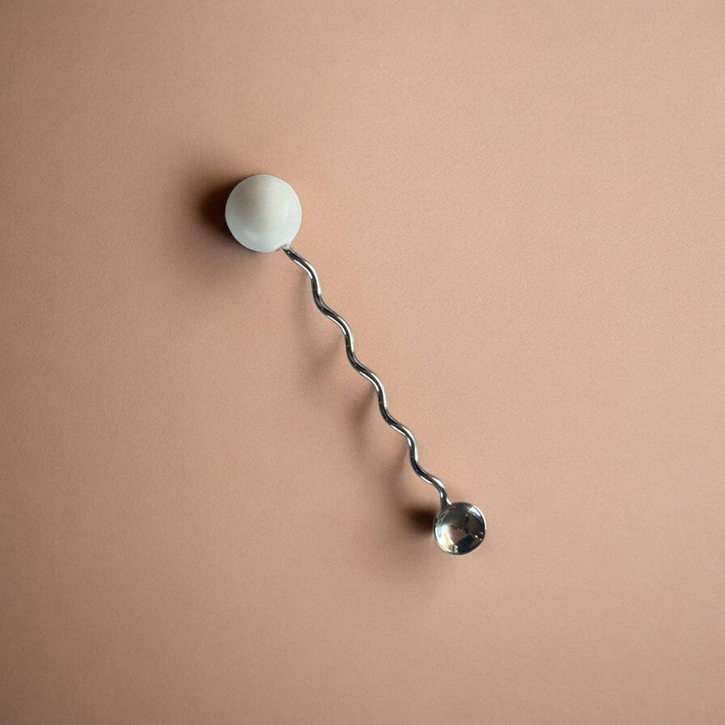 Wall-mounted lamp with a curved arm and spherical ends on a beige background