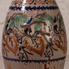 Close-up of a ceramic vase or bottle with a glossy beige glaze and hand-painted floral and bird motifs in blue, green, brown, and black.