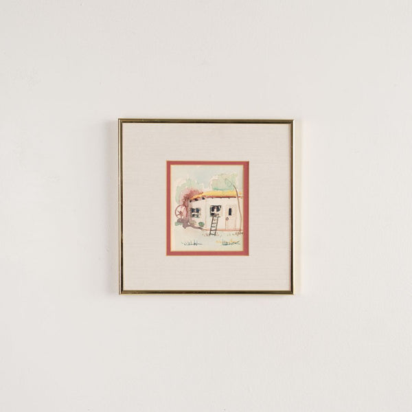 Framed artwork of a small house with a ladder on a white wall