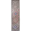 A long rectangular area rug with a geometric tribal pattern in pink, blue, gray, and beige on a white background.