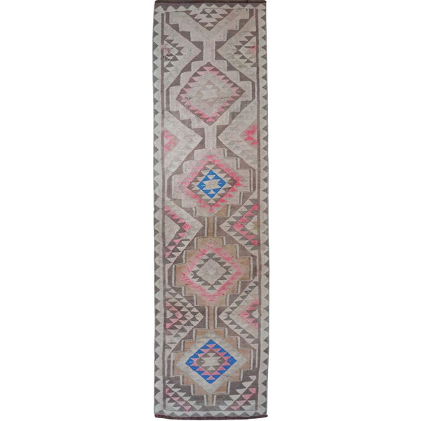 A long rectangular area rug with a geometric tribal pattern in pink, blue, gray, and beige on a white background.