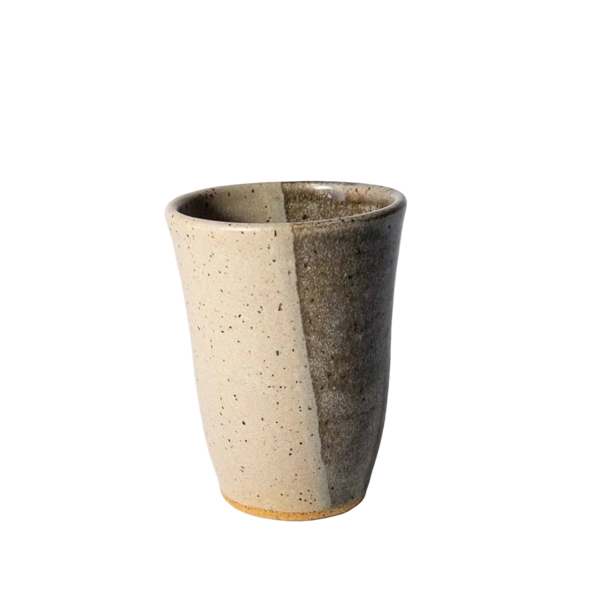 A handmade ceramic cup with a split glaze design, featuring a speckled beige side and a dark brown side, set against a plain white background.