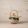 Ceramic teapot with decorative elements on a textured surface
