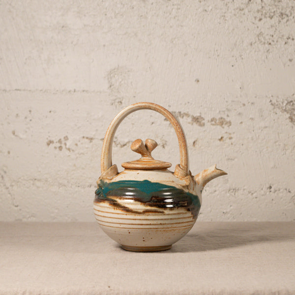 Ceramic teapot with decorative elements on a textured surface