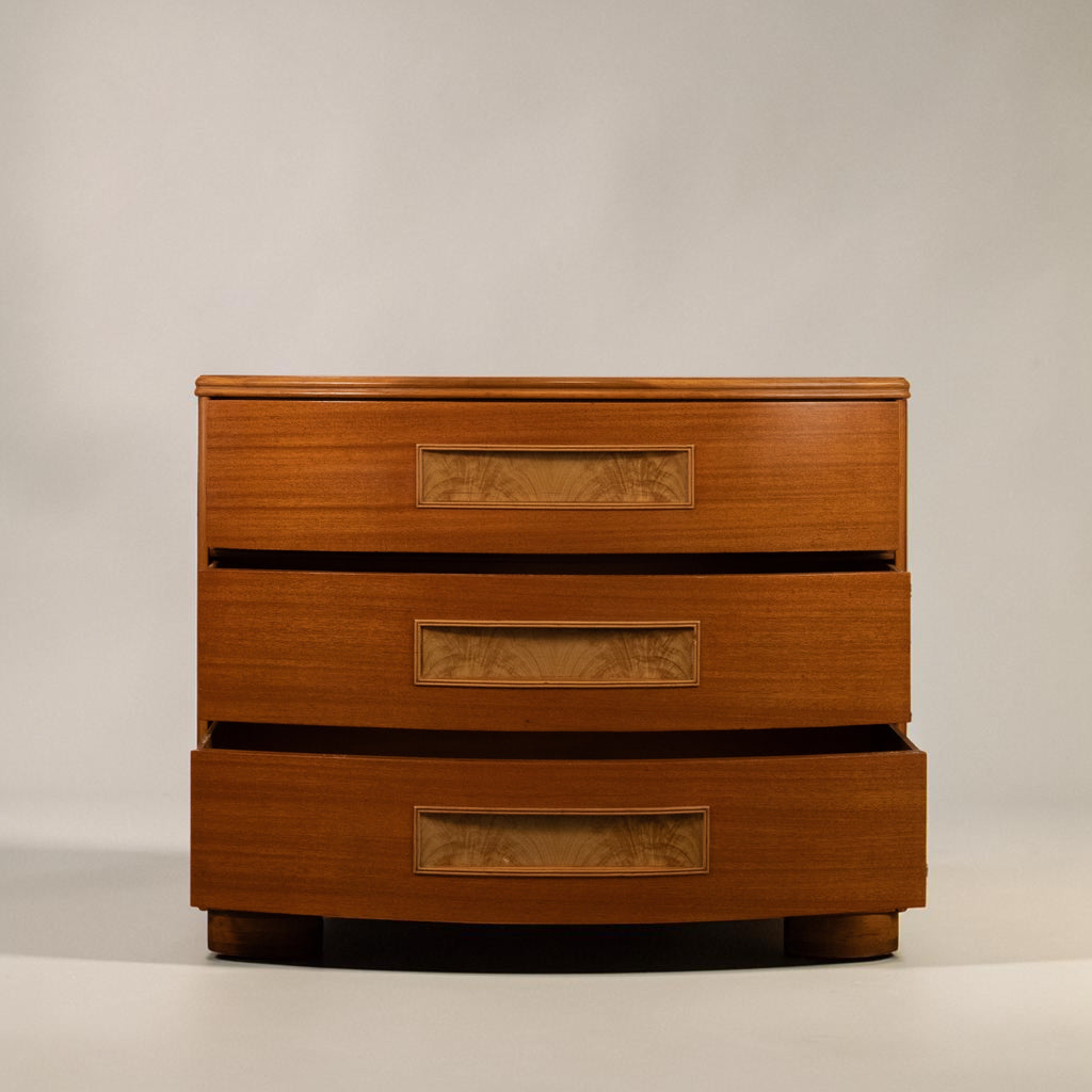 A mid-century modern wooden three-drawer chest with a warm honey-brown finish and decorative inset woodgrain panels on each drawer front, set against a neutral light gray background.