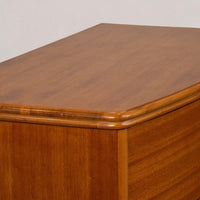 Close-up of a wooden cabinet or dresser showing the top surface, rounded corner trim, and wood grain finish against a plain light background.