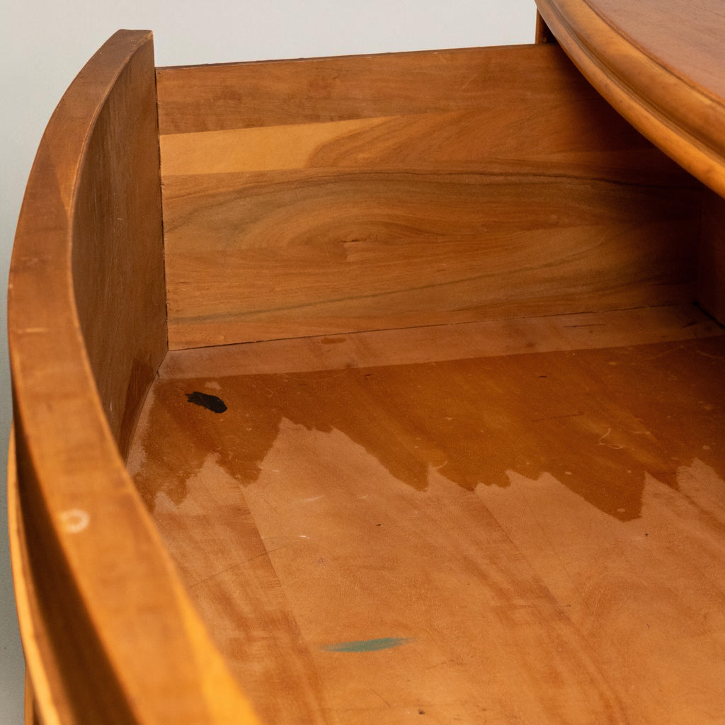 Close-up of a wooden furniture piece showing the interior side of a curved drawer or shelf with a glossy medium-brown wood finish.