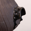 Close-up of a dark brown textured ceramic vessel with a glossy black dripping glaze detail on a light off-white background.