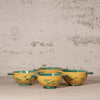 Set of yellow bowls with green accents on a textured surface and background