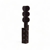 A dark brown wooden sculpture of a traffic light with three circular signal lights on top and a rectangular base with raised circular details, set against a plain white background.