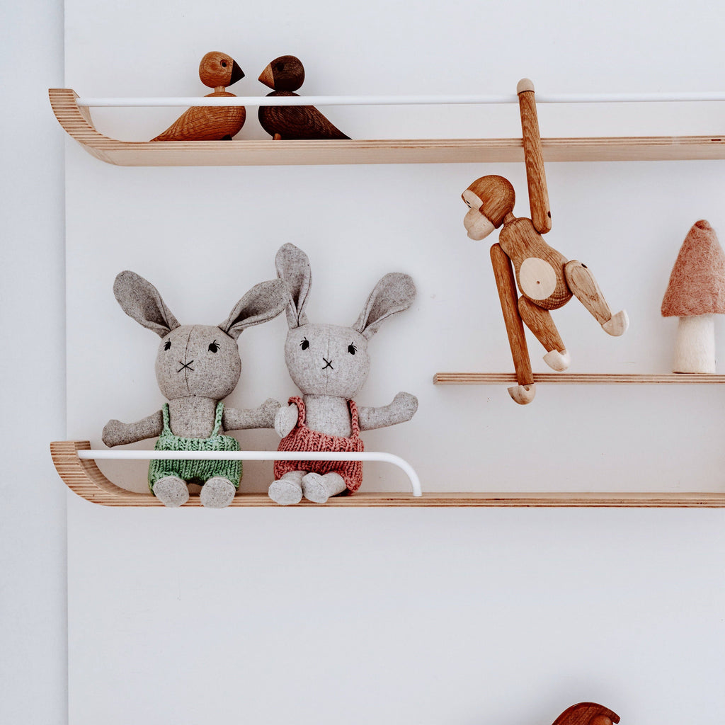 Lionel Rabbit in green and pink sitting on a shelf with other toys around