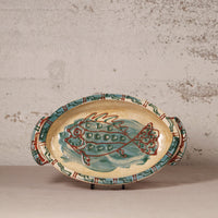 Ceramic platter with fish design on a textured surface