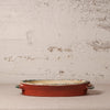 Decorative terracotta dish with floral patterns on a textured surface