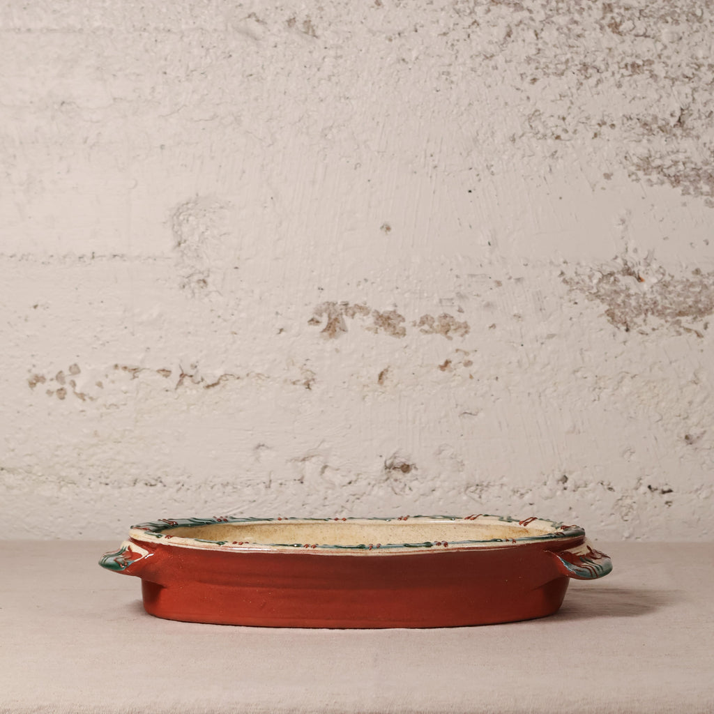 Decorative terracotta dish with floral patterns on a textured surface