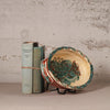 Ceramic plate with fish design next to two books on a textured surface.
