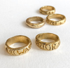 Gold rings with engraved text on a white background
