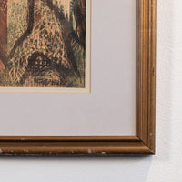 A close-up of a framed art print hanging on a white wall, showing the corner of the frame, a cream mat, and part of a textured, abstract print in earthy brown, black, and beige tones.