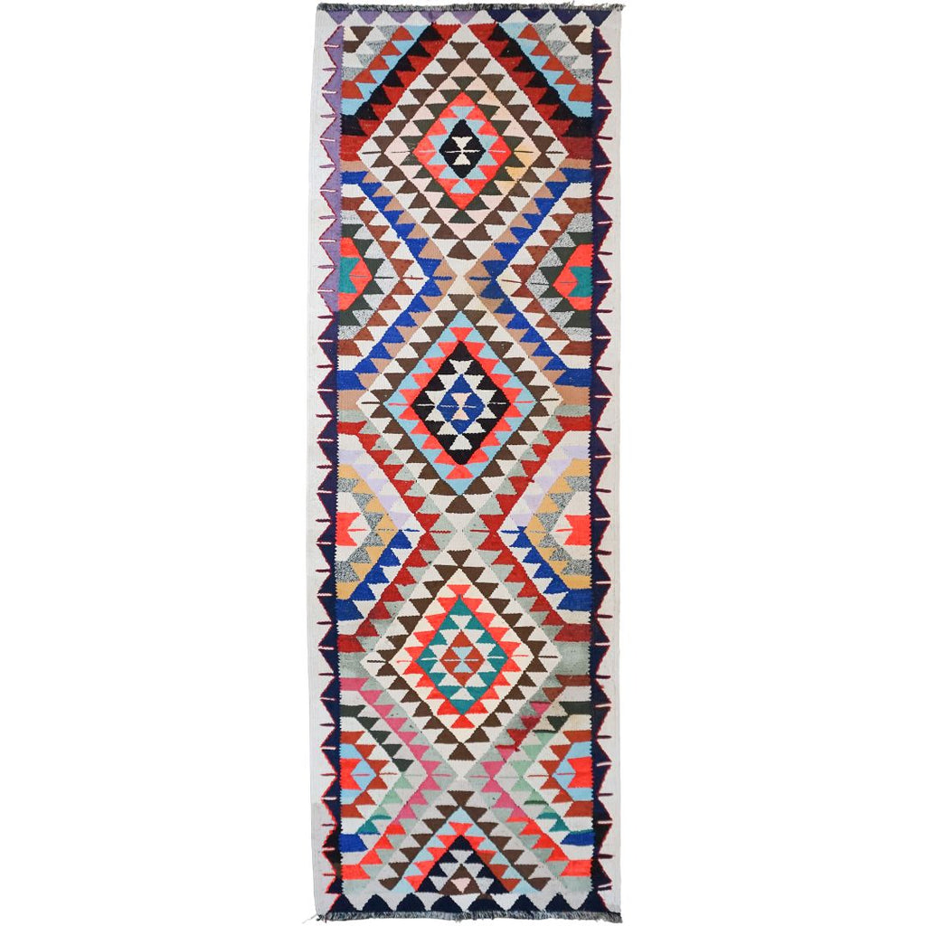 A long rectangular woven runner rug with a bold geometric tribal pattern in multiple colors including red, blue, black, beige, and white, shown flat against a white background.