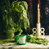 NUEVE LEONES Candle green displayed with green leaves in a vase 