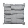 A square throw pillow made from a light beige woven textile with horizontal dark gray stripes, displayed on a rustic gray wooden plank surface.