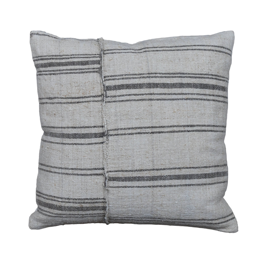 A square throw pillow made from a light beige woven textile with horizontal dark gray stripes, displayed on a rustic gray wooden plank surface.