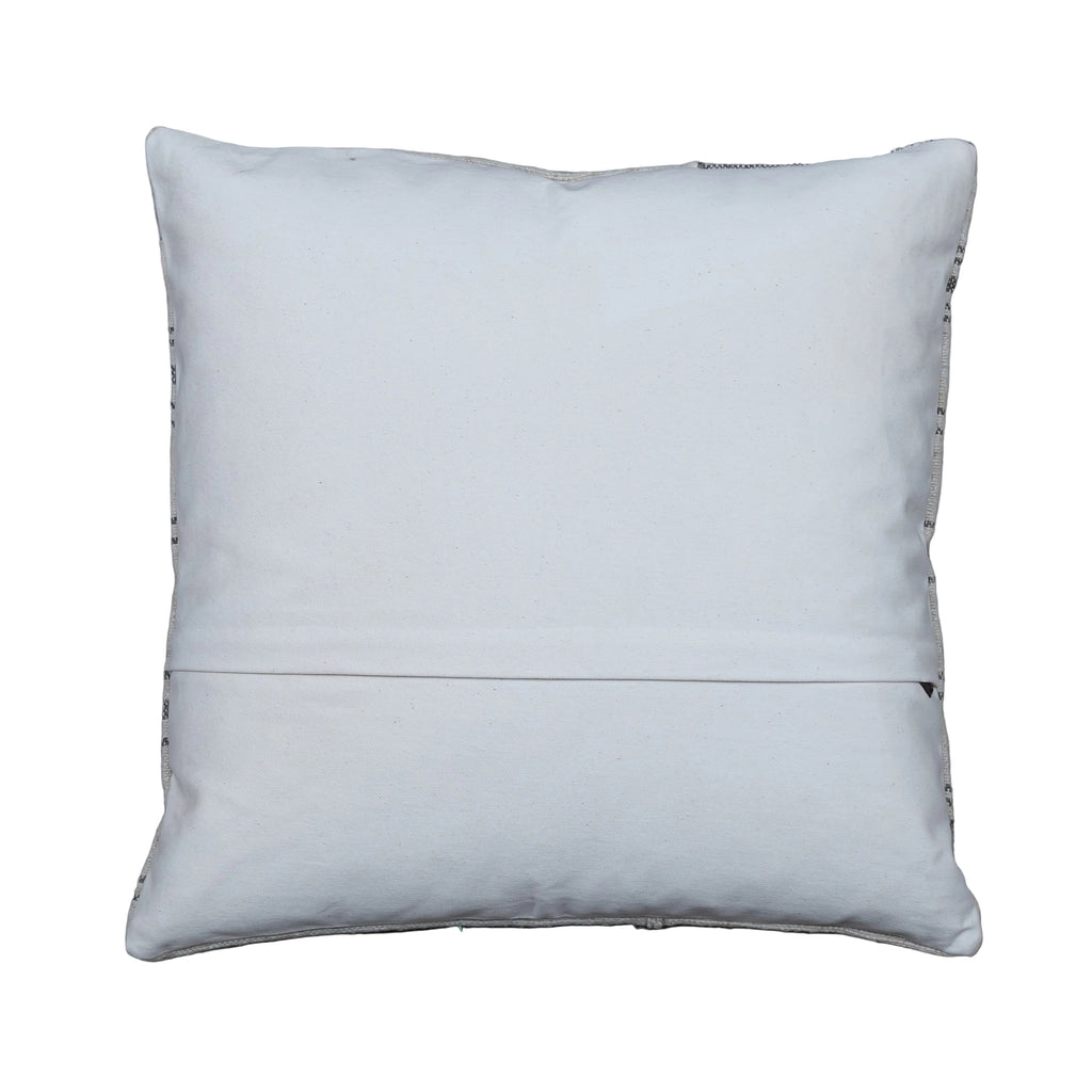 A square white throw pillow with a stitched hem and decorative bead trim along the edges, displayed flat on a gray wooden plank surface.