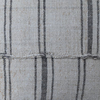 Close-up of woven fabric with a light beige base and vertical dark charcoal gray stripes, showing the textile texture and a horizontal stitched seam.
