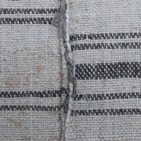 Close-up of a woven textile surface with a natural off-white base and dark charcoal gray horizontal stripes, showing the texture and weave detail.