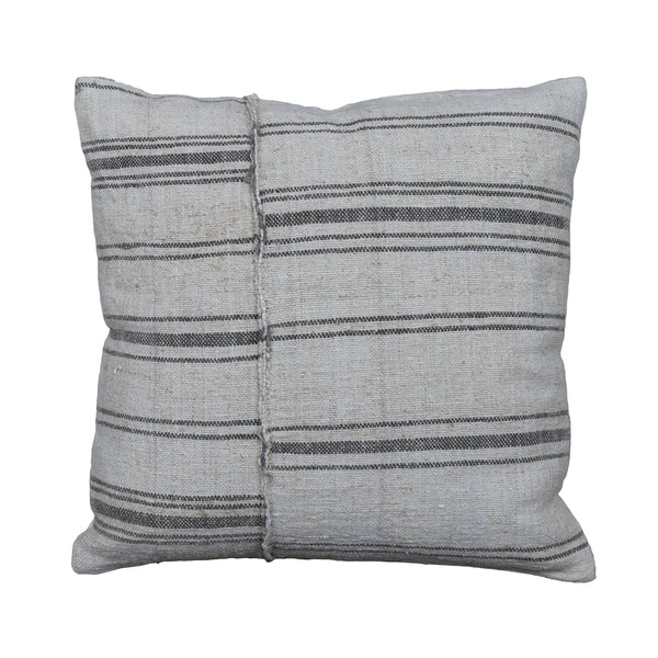 A square throw pillow made from a light beige woven textile with horizontal dark gray stripes, displayed on a rustic gray wooden plank surface.