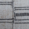 Close-up of a woven textile surface with a natural off-white base and dark charcoal gray horizontal stripes, showing the texture and weave detail.