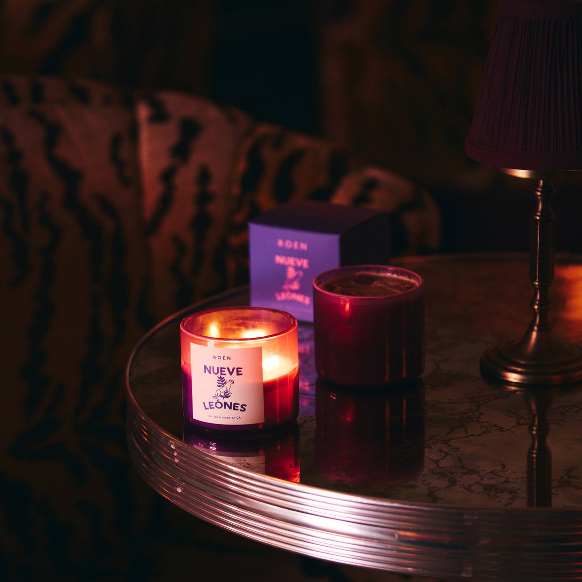 NUEVE LEONES Candle  lit next to a box on a table