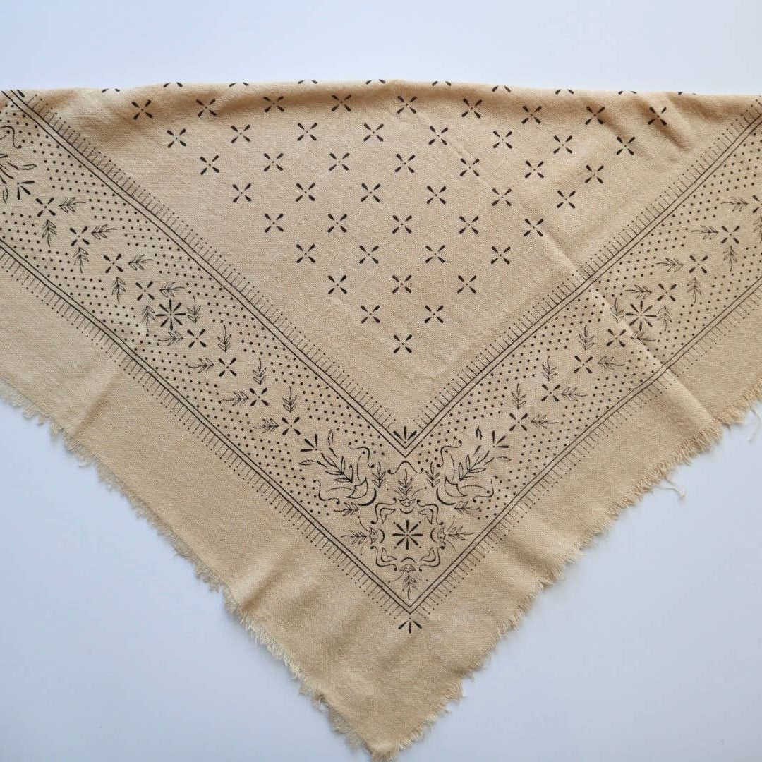 Beige fabric with intricate black embroidery on a white background