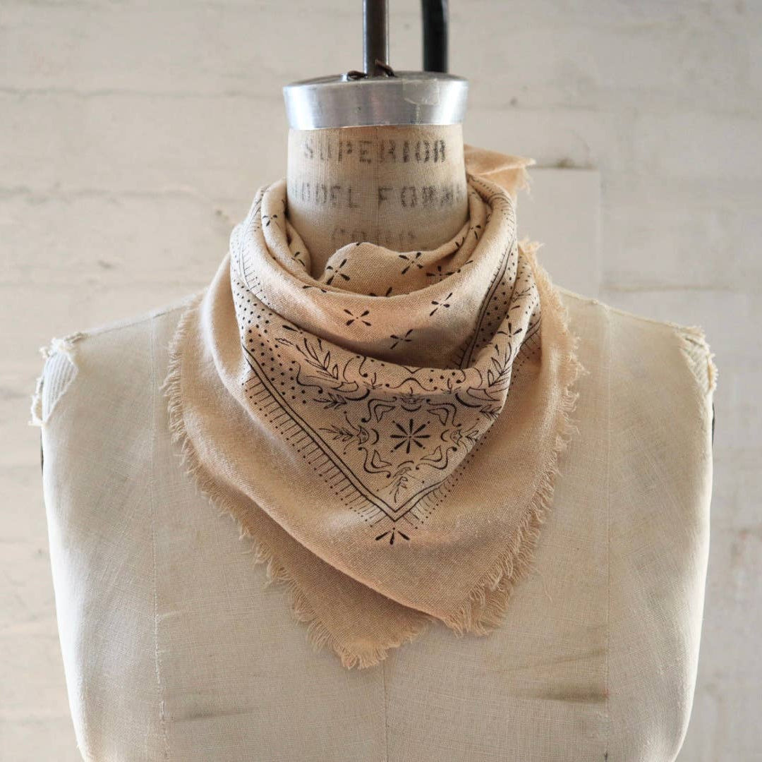 Beige bandana with intricate patterns on a mannequin against a light background