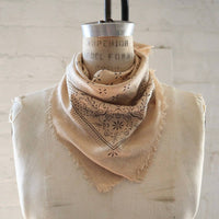 Beige bandana with intricate patterns on a mannequin against a light background