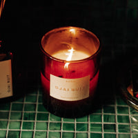 Candle in a red holder with a label on a green surface